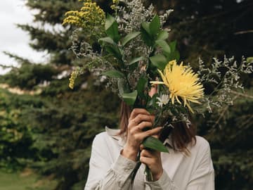 Frau mit Blumen vor Gesicht