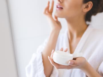 Frau mit Creme-Tiegel in der Hand