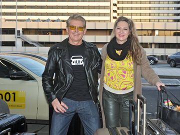 Markus Mörl und Yvonne König stehen mit Koffern vor einem Gebäude