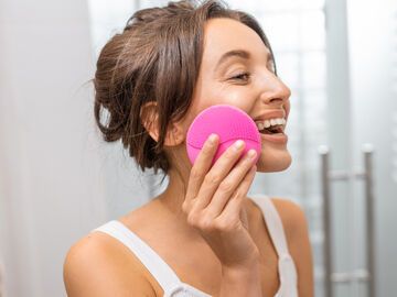 Frau reinigt Gesichts mit Silikonbürste