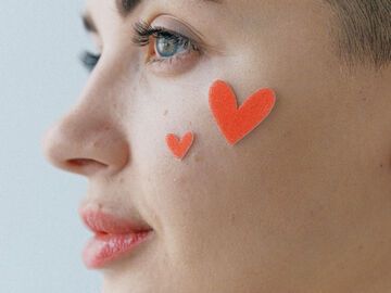 Frau mit Herz-Stickern im Gesicht
