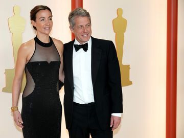 Anna Eberstein und Hugh Grant stehen Arm in arm auf dem Teppich bei den Oscars 2023
