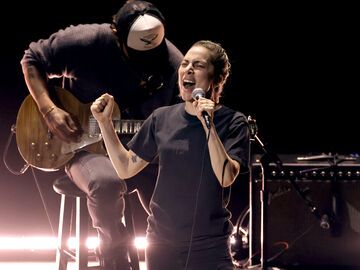 Lady Gaga singt auf der Bühne mit Mikro in der Hand und aufgerissenem Mund im Hintergrund sitzt ein Bassist auf einem Hocker