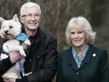 Paul O'Grady mit Hund auf dem Arm, Queen Consort Camilla lacht neben ihm