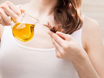 Frau pflegt trockene Haarspitzen mit Olivenöl