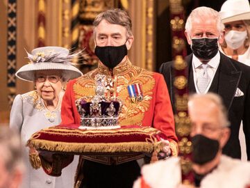 Prinz Charles läuft neben Queen Elizabeth Diener vor ihnen trägt Krone