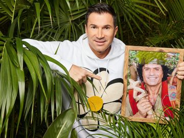 Lucas Cordalis hält ein Foto von Costa Cordalis als Dschungelkönig in der Hand.