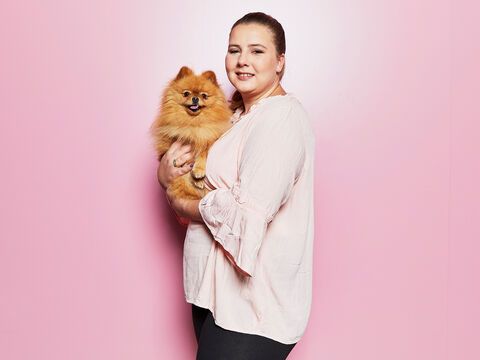 Sarafina Wollny mit Hund Feivel auf dem Arm vor einer pinken Wand