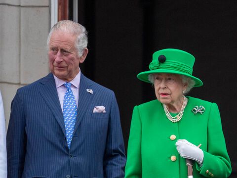 König Charles III. und seine Mutter Queen Elizabeth II. stehen nebeneinander und schauen ernst