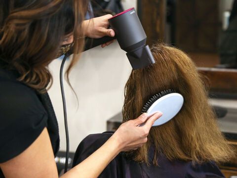 Frau bekommt Haare mit Dyson geföhnt