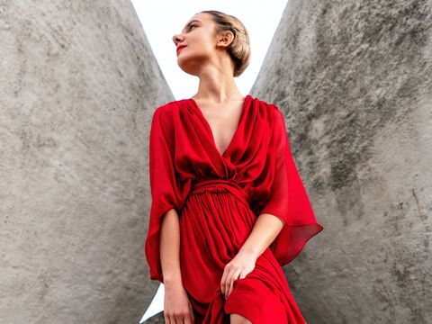 Frau im roten Seidenkleid vor Steinwand