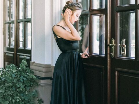 Frau mit Dutt steht im schwarzen Kleid vor Tür