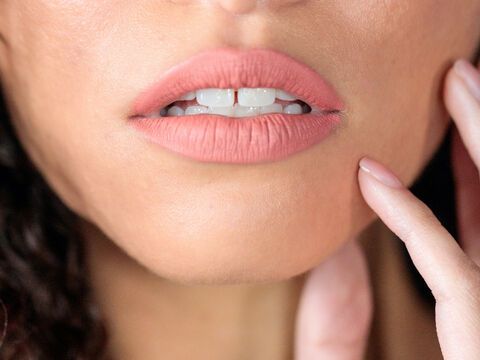 Frau mit Zahnlücke trägt mattem Lippstift