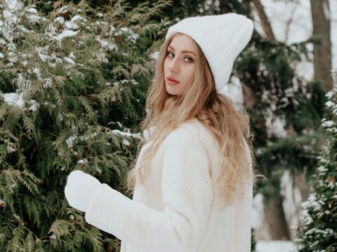 Frau mit weißem Winter-Look vor verschneiten Tannen