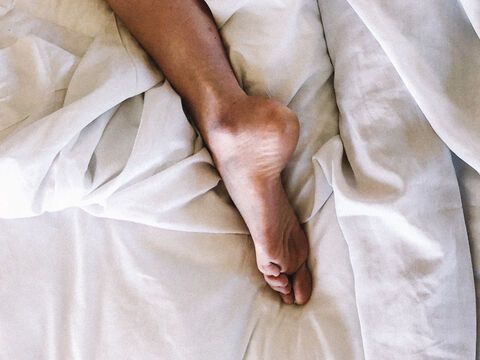 Fuß auf weißer Bettwäsche