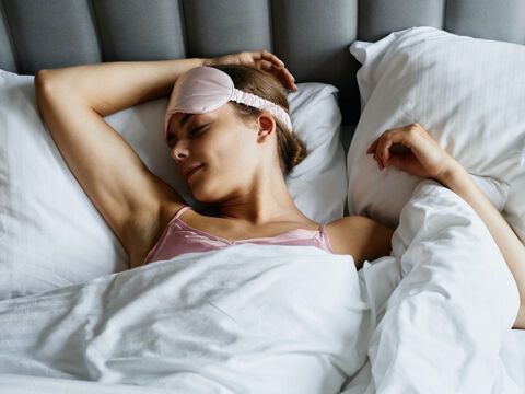 Frau liegt mit Schlafmaske im Bett