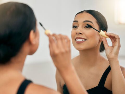 Frau trägt Mascara vor Spiegel auf