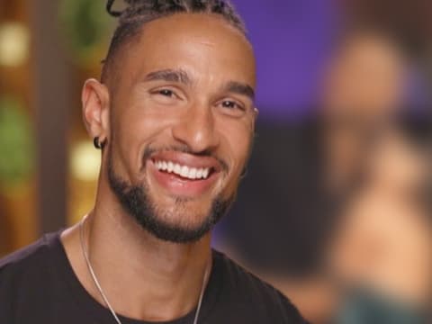 David Jackson lächelt, im Hintergrund David verschwommen mit einer "Bachelor"-Kandidatin