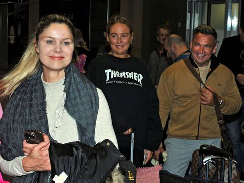 Yvonne Woelke lächelnd am Flughafen, Peter Klein im Hintergrund