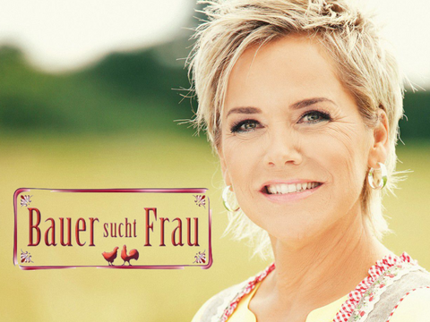 Inka Bause lächelt in Dirndl - mit "Bauer sucht Frau"-Logo