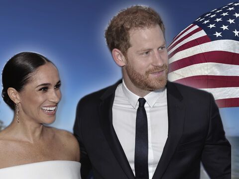 Herzogin Meghan und Prinz Harry vor USA-Flagge, beide lächeln.