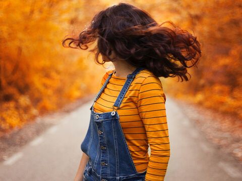 Frau vor Herbst-Hintergrund schwingt Haare