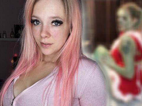 Anne Wünsche mit rosa Haaren, im Hintergrund sieht man sie verschwommen als Grinch verkleidet