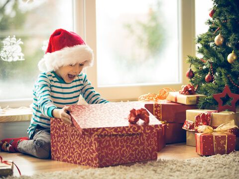 Kind öffnet Weihnachtsgeschenk und freut sich