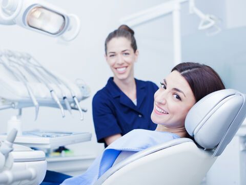 Zahnärztin und Patientin lächeln in die Kamera 