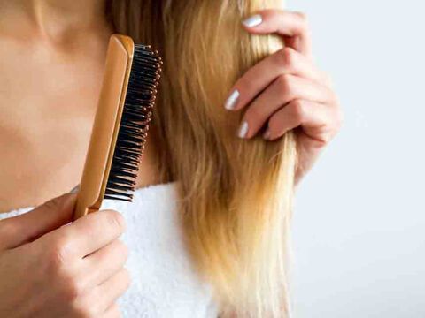 Frau kämmt Haare mit Keratin und Arganöl