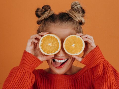 Frau hält sich frische orangen vor die Augen und lacht