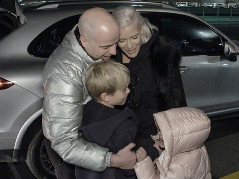 Daniel und Oksana Kolenitchenko umarmen ihre Kinder draußen vor einem Auto