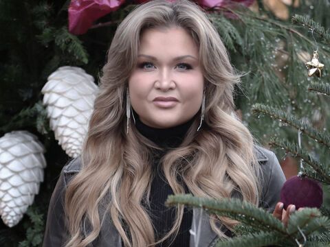 Sophia Thiel steht zwischen Christbäumen und hält eine Weihnachtskugel in der Hand