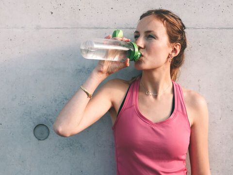 Frau in sportlichen Top trinkt aus einer Flasche