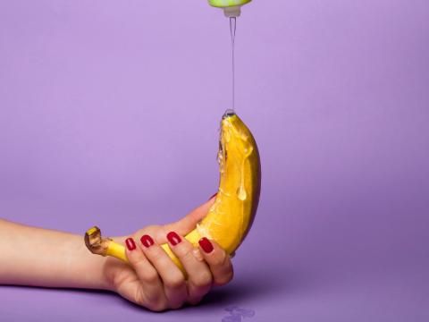 frau hält banane mit gleitgel in der hand