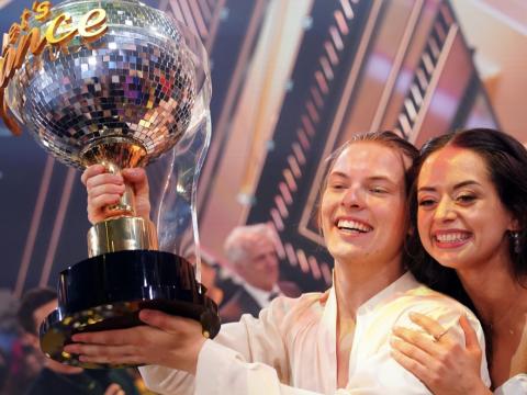 Gabriel Kelly hält den "Let's Dance"-Siegerpokal hoch und Malika Dzumaev umarmt ihn