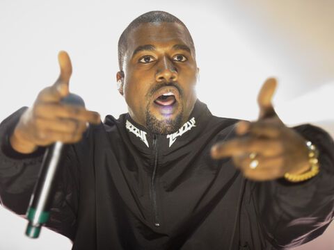 Kanye West mit Mikrofon und Fingerpistole.
