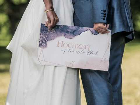 Brautpaar mit einem "Hochzeit auf den ersten Blick"-Schild
