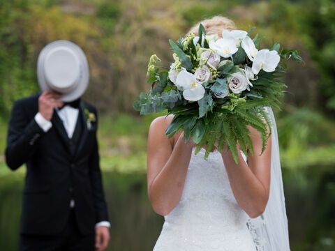 eine Braut im Vordergrund, ein Bräutigam im Hintergrund