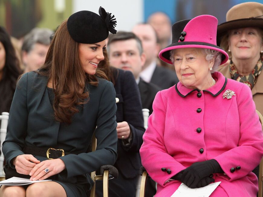 Prinzessin Kate und Queen Elizabeth II. sitzen nebeneinander und lachen.