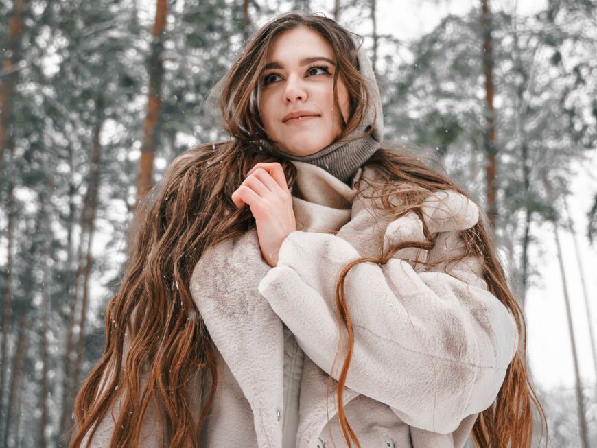 Frau mit sehr langen Haaren im Winterwald