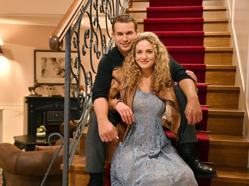 Lea Wegmann und Florian Frowein sitzen auf einer Treppe, sie sitzt zwischen seinen Beinen