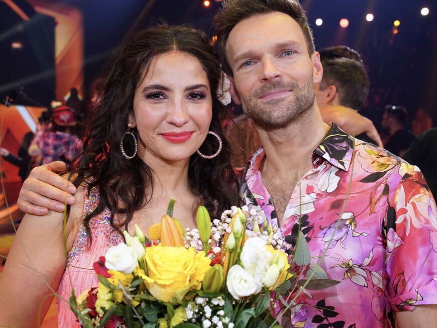 Chryssanthi Kavazi hält einen Blumenstrauß in der Hand und Vadim Garbuzov umarmt sie