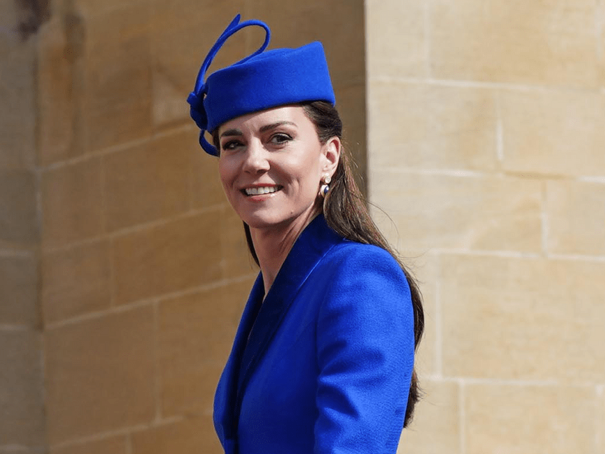 Prinzessin Kate im blauen Mantelkostüm lächelt in die Kamera.