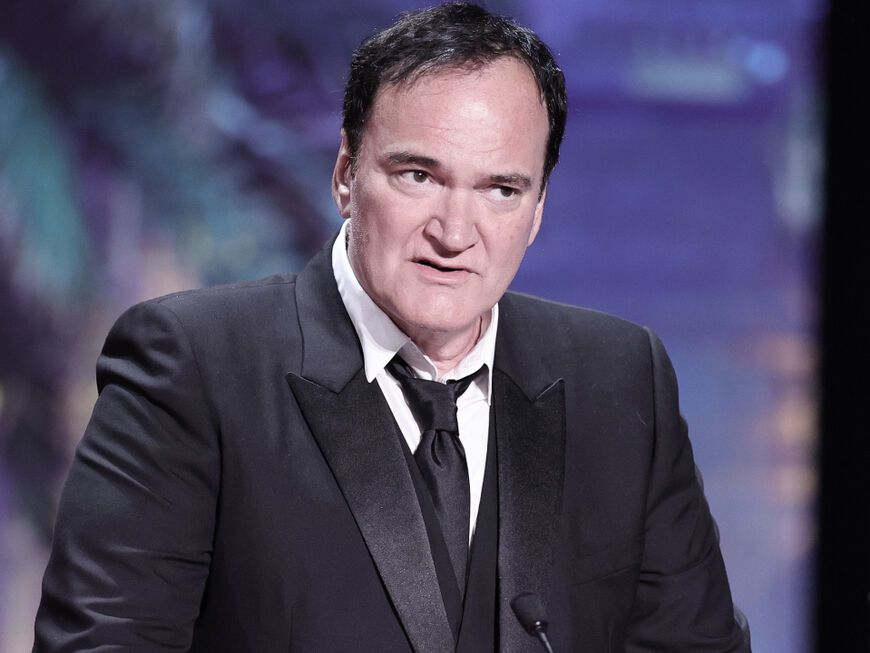 Quentin Tarantino steht mit ernstem Gesichtsausdruck am Mikrofon