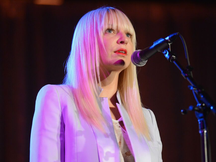 Sängerin Sia guckt bedrückt mit Mikrofon