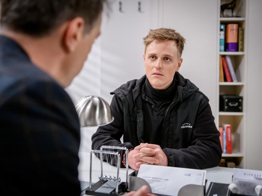 Sturm der Liebe Max guckt ernst mit verschränkten Händen auf dem Tisch