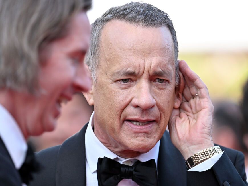 Tom Hanks hält sich die Hand ans Ohr, um besser hören zu können