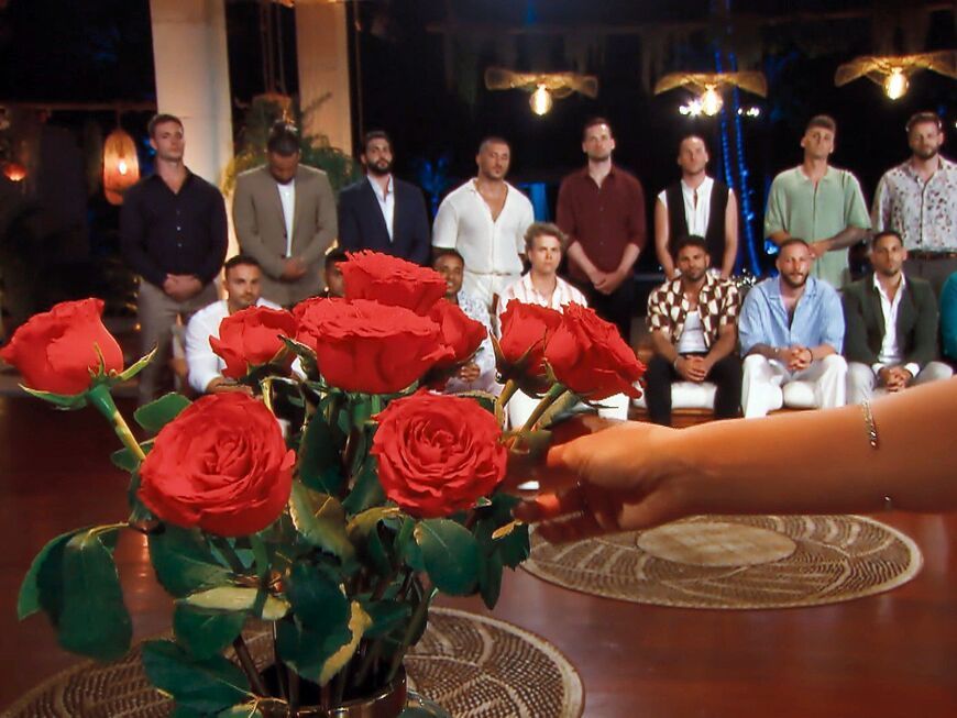 "Die Bachelorette" 2023 - Nacht der Rosen mit Rosenstrauß und Kandidaten im Hintergrund 