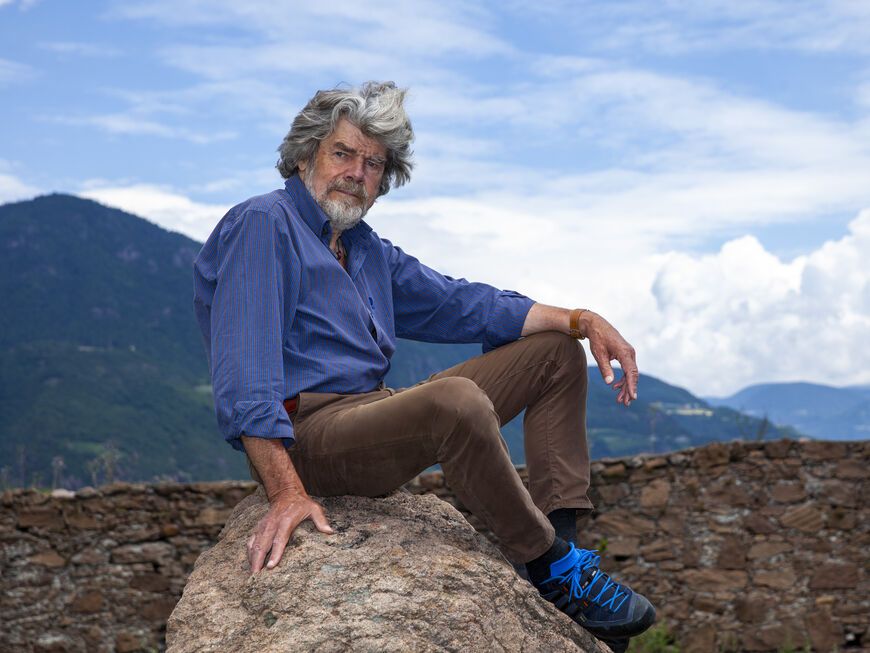 Reinhold Messner sitzt auf einem Stein